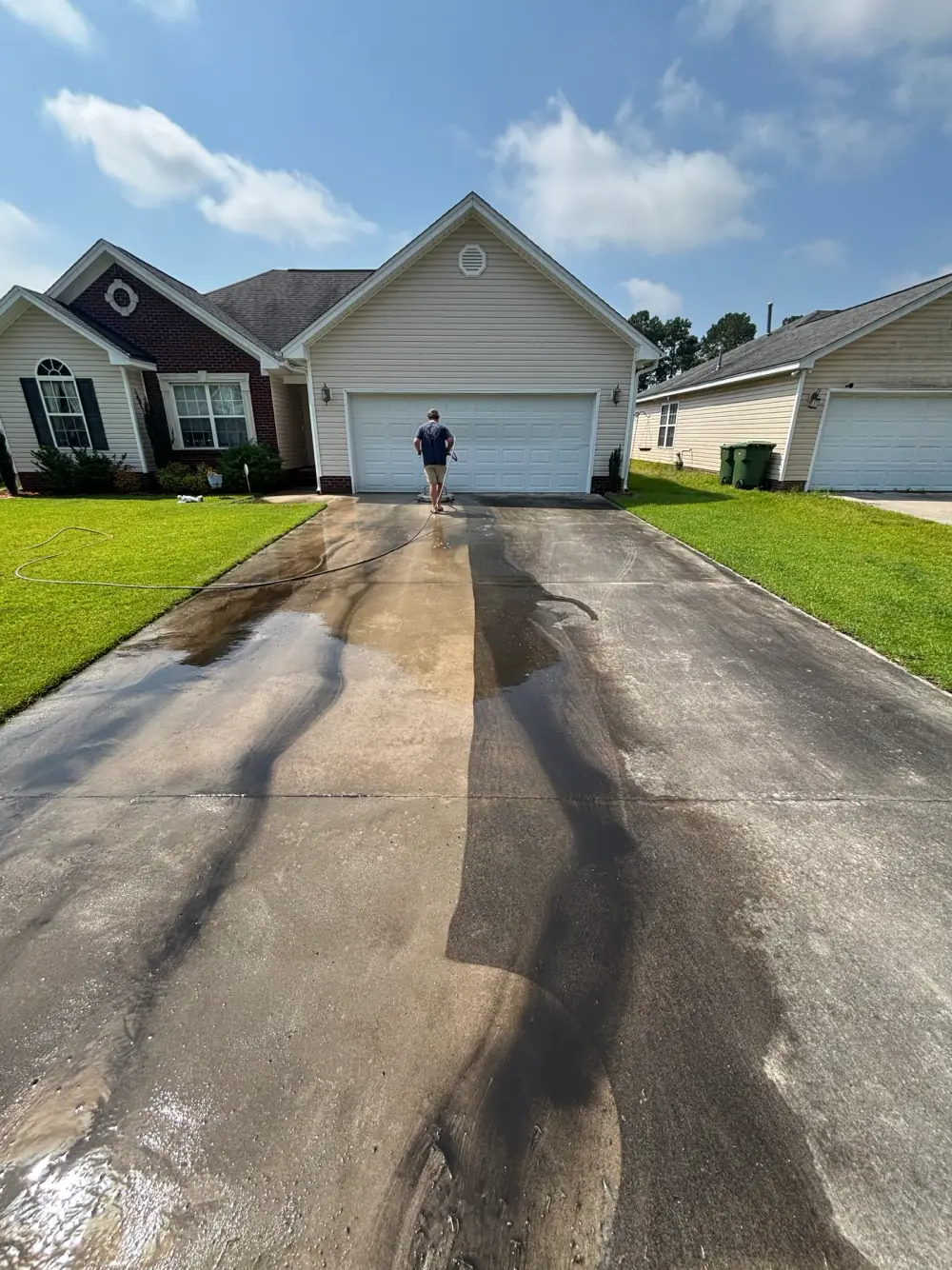 Pressure washing underway on a residential driveway